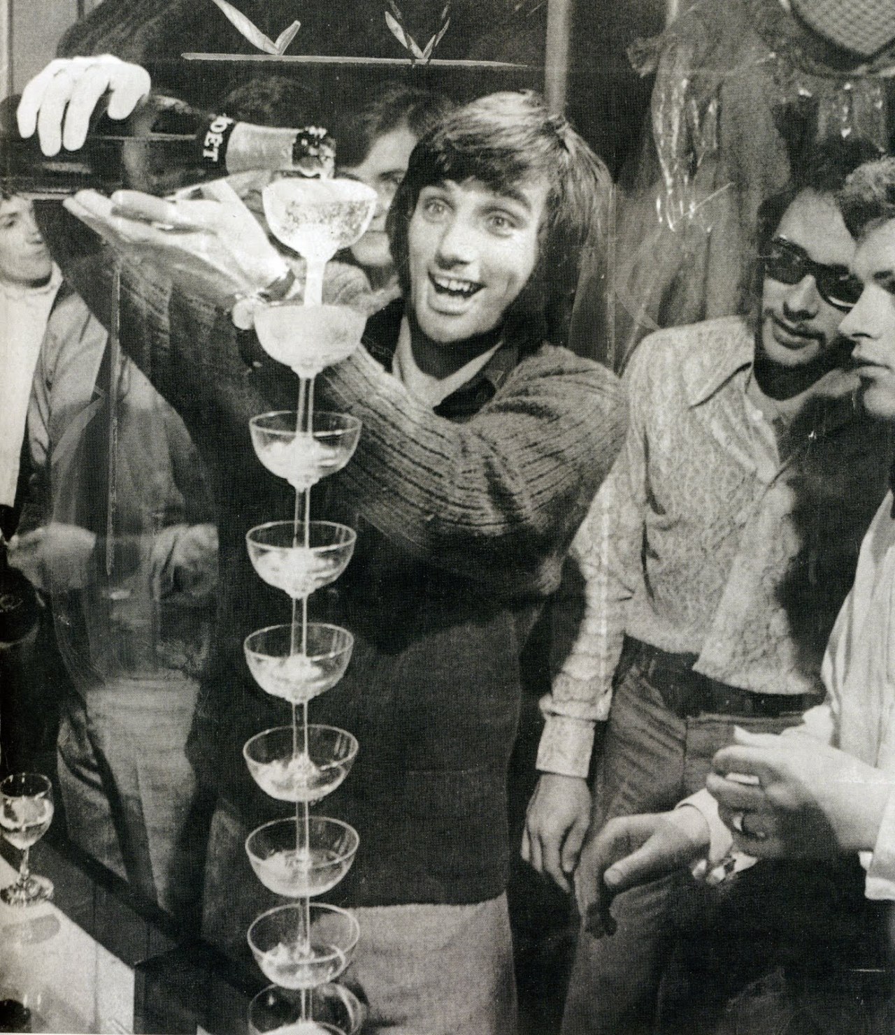 George Best filling some glasses with wine