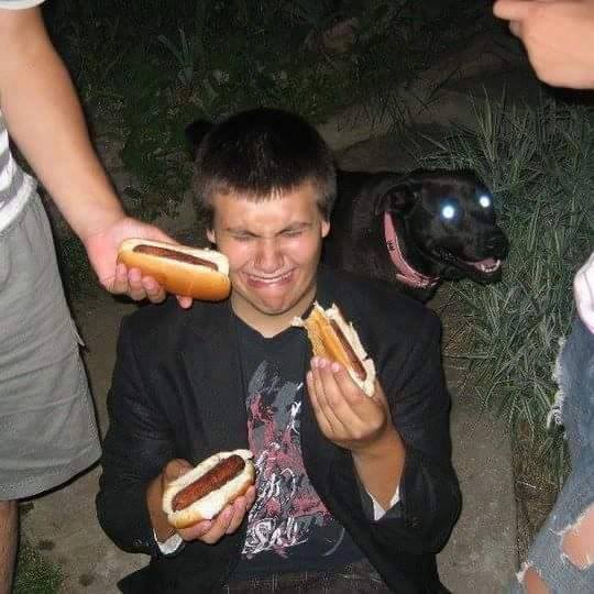 boy crying as he is forced to eat many hotdogs as a dog glowers in the background