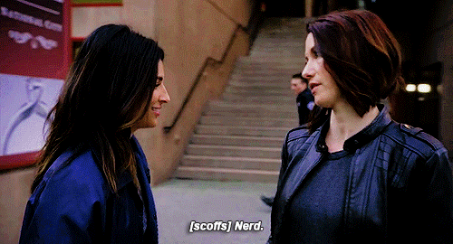 Gif of Maggie Sawyer smiling as she walks around Alex Danvers (from Supergirl), scoffing as she calls Alex a nerd. Gif from http://68.media.tumblr.com/67314fc86ab5ec070bdd00599ad68d65/tumblr_om1ezk9yp91rxc6mvo1_500.gif