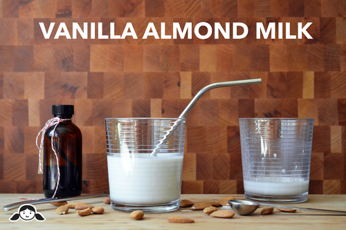 Two glasses of almond milk with a bottle of vanilla extract.