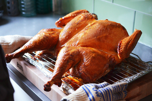 A Spatchcock Turkey with golden brown skin is resting on a cutting board before serving.
