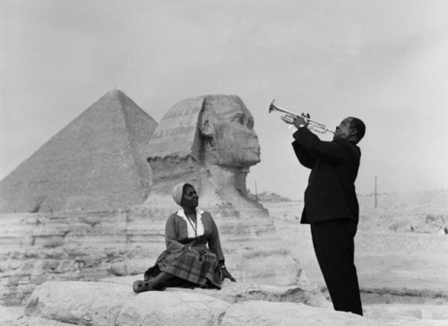 Louis Armstrong plays trumpet for his wife, Lucille, in front of the Great Sphinx and pyramids in Giza, Egypt (1961).