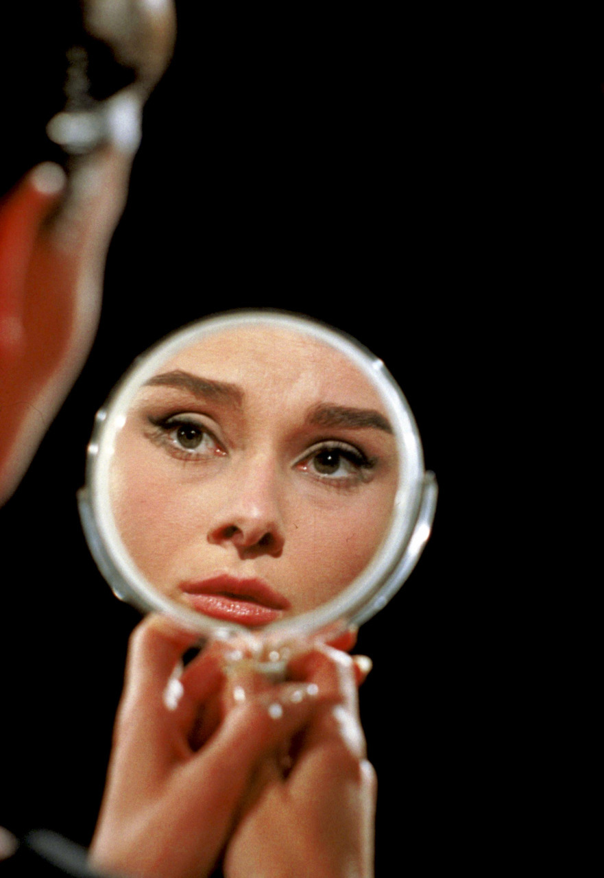 Audrey Hepburn beholds her reflection in a mirror on the set of Funny Face, portrait by Richard Avedon, 1956.