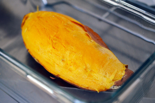 A cooked microwaved yam cut in half in a glass container.