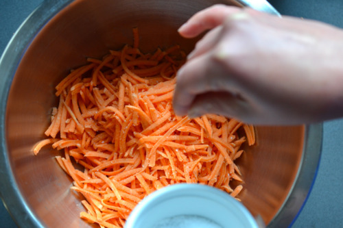 An overhead shot of shredded sweet potatoes in a metal mixing bowl.