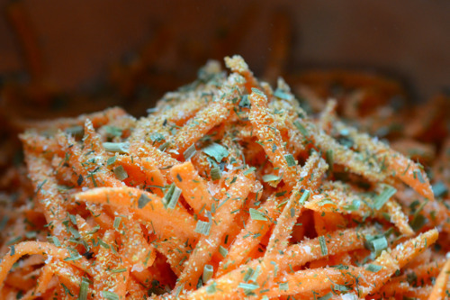 A closeup shot of shredded sweet potato with dried herbs and spices.