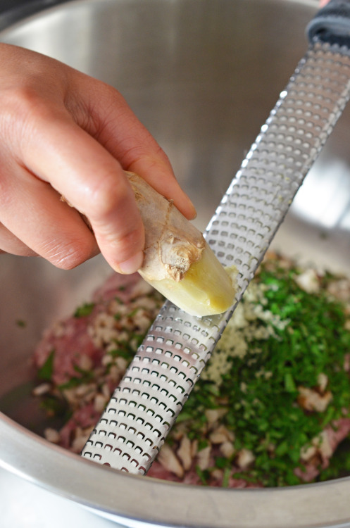 A frozen piece of ginger is being zested with a Microplane rasp grater.