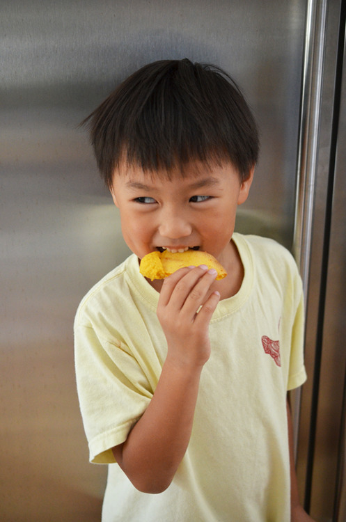A young child biting into a grain-free pita bread.