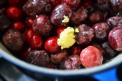 Cranberries and cherries in a pot with ginger for paleo cran-cherry sauce.