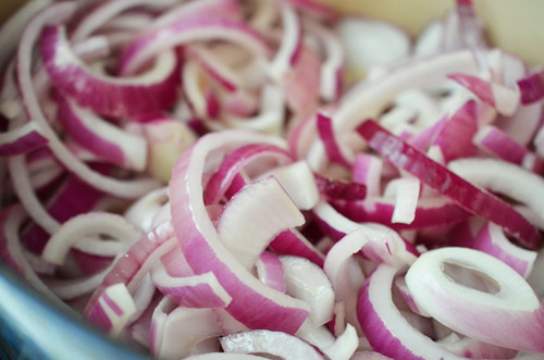 Sliced red onions in a Dutch oven.