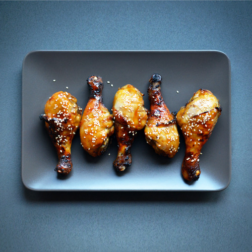 Orange Sriracha Chicken laid in a row on a plate.
