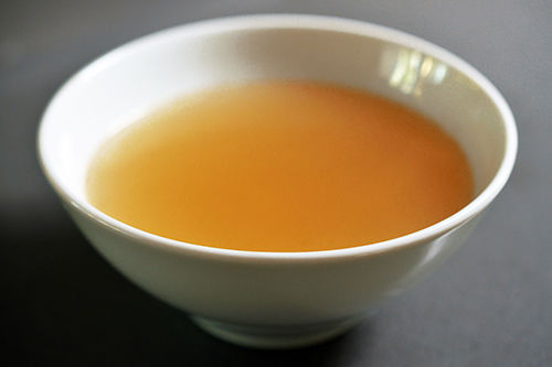 A side shot of a white bowl filled with bone broth