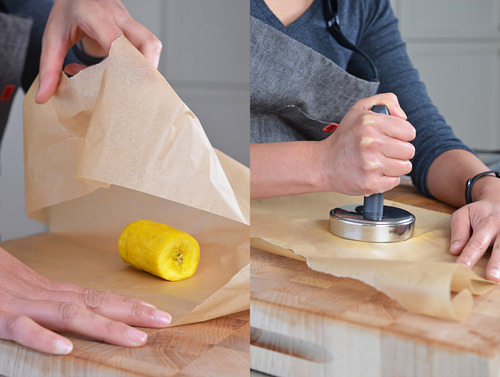 In the left image, someone is about to wrap a piece of parchment paper around a fried piece of plantain. On the right, the person is smashing the plantain in between the parchment paper.