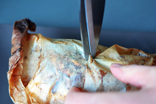 Scissors snip open a package of Fish en Papillote with Citrus, Ginger, & Shiitake 