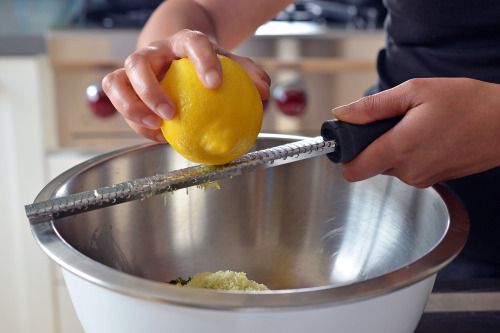 Someone is zesting lemon peel into a large bowl.