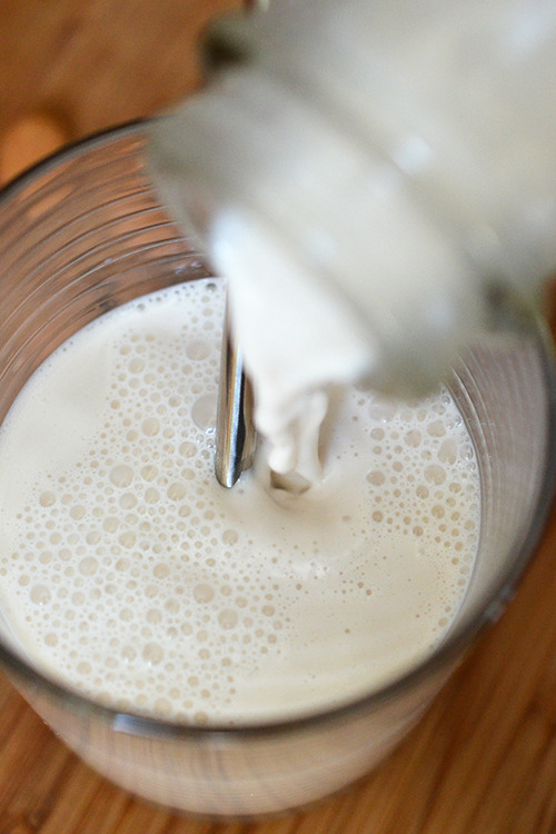 Pouring the vanilla almond milk into a glass cup.