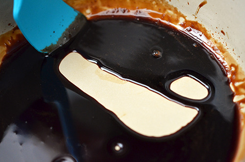 Reducing the balsamic vinegar in a pot with a rubber spatula scraping the bottom to check the consistency.