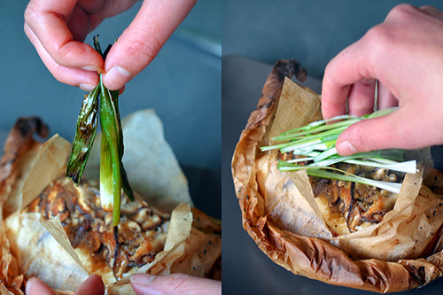 Someone removing the wilted green onions from the papillote and adding freshly sliced scallions. 