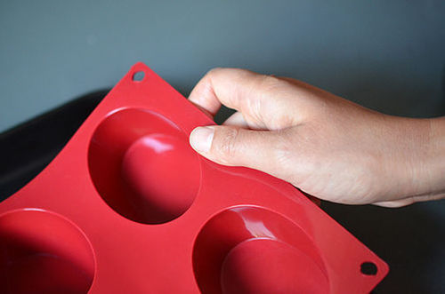 A hand holding up a red silicone ice mold