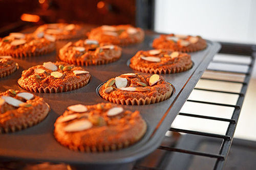 An open oven door and a muffin tin filled with Paleo Pumpkin and Carrot Muffins 