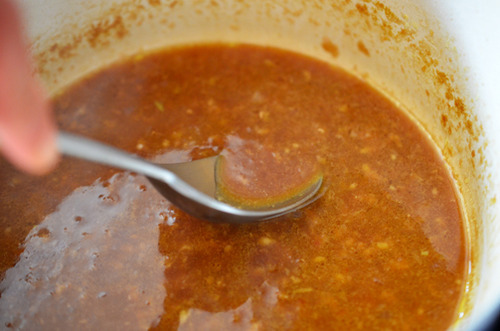 A spoon is stirring the Asian Citrus Dressing in the pot.