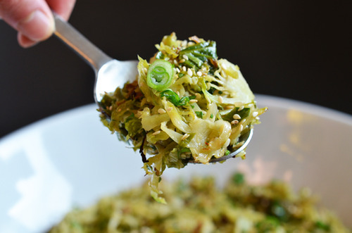 A spoon scooping Warm Brussels Sprouts Slaw with Asian Citrus Dressing 