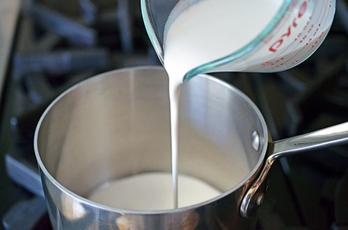 Pouring coconut milk into a small saucepan to warm it up to make paleo chocolate ganache.