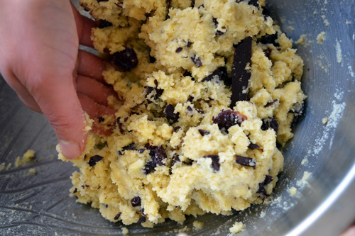 Someone mixing up the batter in a large bowl for grain-free dark chocolate cherry scones.