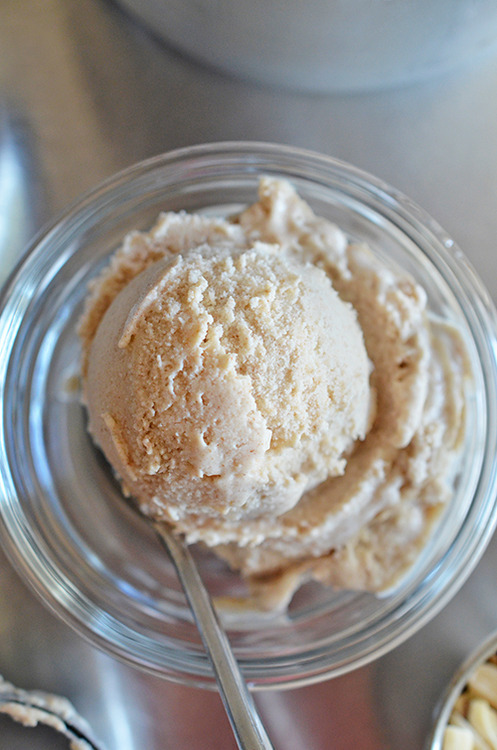 An overhead shot of a scoop of paleo and Dairy-Free Vanilla Ice Cream in a clear glass with a spoon.