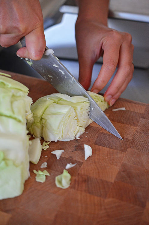 Someone chopping up cabbage on a cutting board.