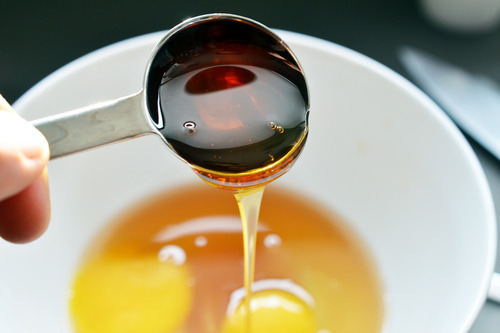 A close up of a spoonful of honey being poured into the wet ingredients.
