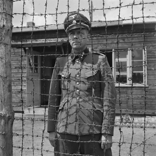 Camp commandant SS-Untersturmführer Karl Peter Berg stands under guard by two Dutch resistance fighters after their arrest at the Amersfoort concentration camp, May 1945. 