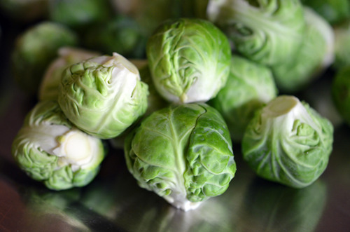 A closeup image of a pile of fresh Brussels Sprouts.