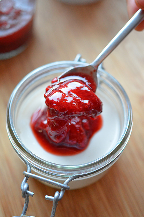 Someone topping the chilled panna cotta with the strawberry balsamic compote.
