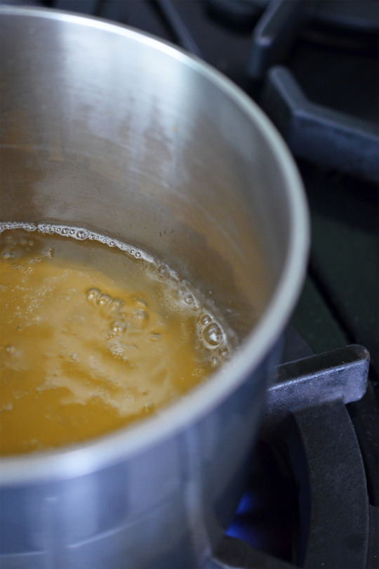 A closeup of broth simmering in a small saucepan.