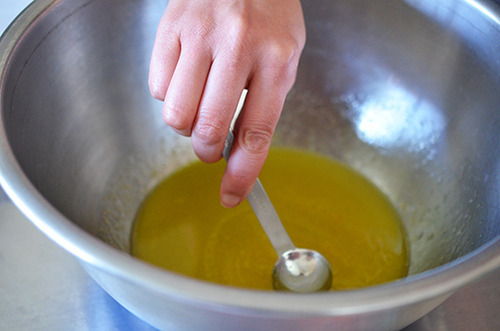Someone stirring the spices with lemon juice in a large metal bowl for honey mustard chicken wings.