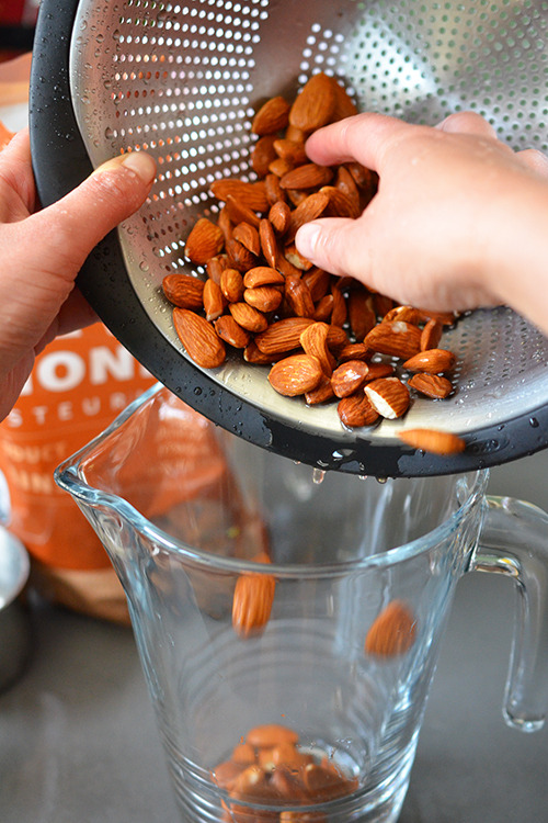Transferring the rinsed almonds into a large glass cup.