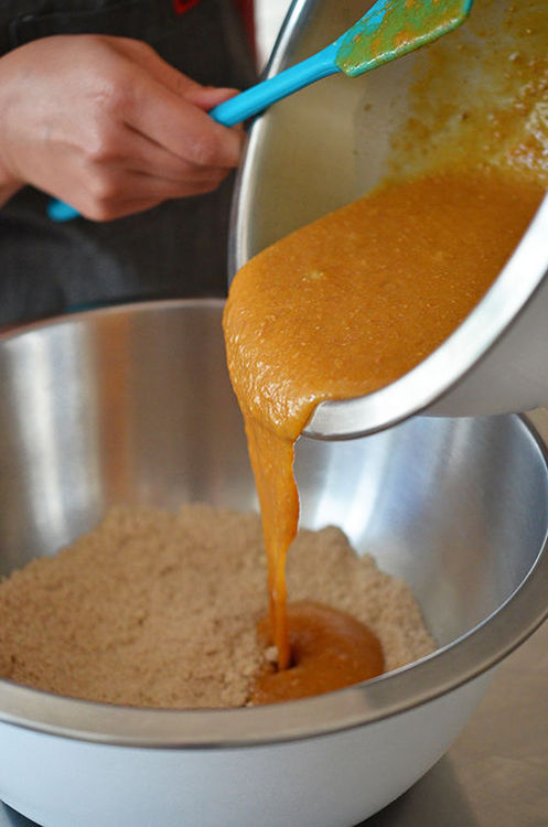 Pouring the wet ingredients into a bowl of dry ingredients for Paleo Pumpkin and Carrot Muffins 