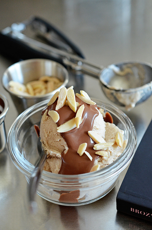 A side shot of a scoop of healthy Dairy-Free Vanilla Ice Cream topped with chocolate ganache and toasted almonds.