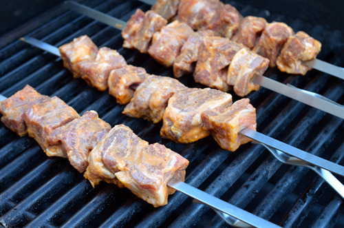 A grill with four skewers of Peachy Pork-a-Bobs, Whole30-friendly grilled pork.