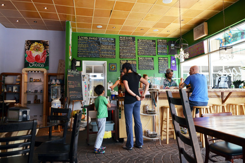 A dark-haired woman and her small son are ordering food at a vegan smoothie restaurant in Hawaii