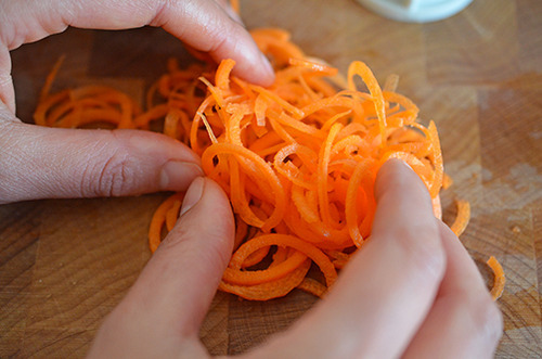Spiralized carrot on a wood cutting board.