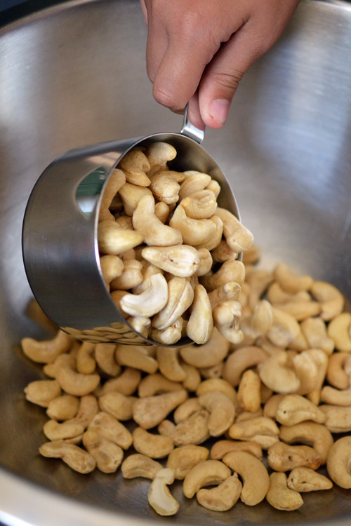 Pouring cashews into a large metal bowl.