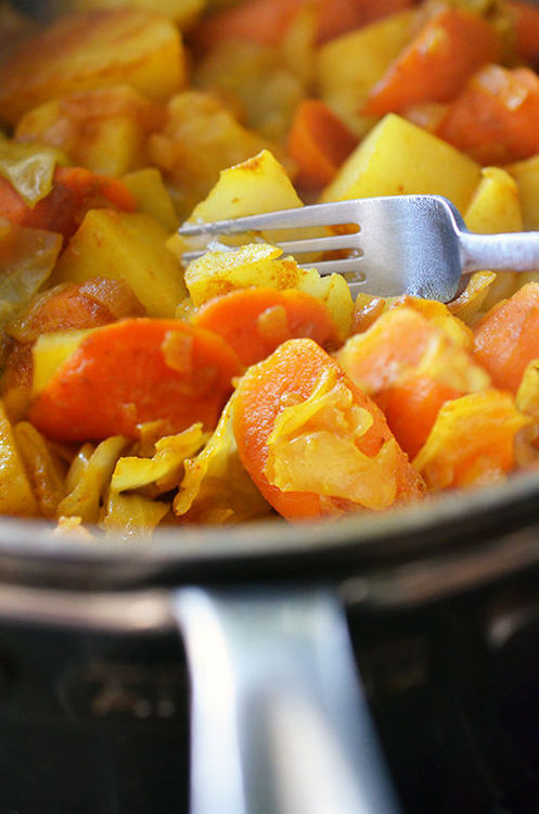 A fork slicing through a piece of cooked potato in Whole30 Atkilt Ethiopian Vegetable Stew.