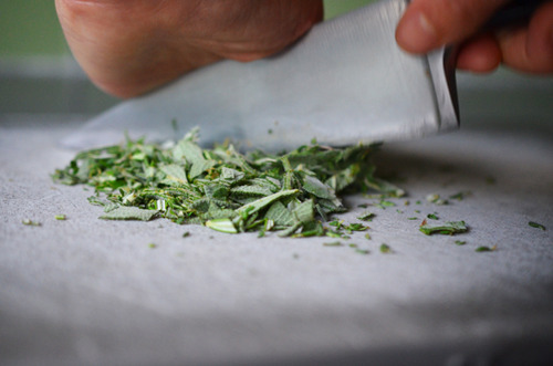 Chopping fresh herbs on a gray cutting board for herb butter.