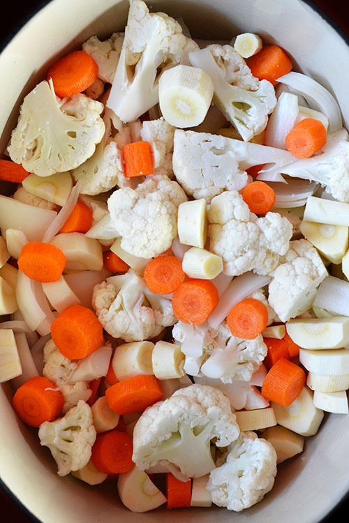 Chopped cauliflower, carrots, and parsnips in a large pot.