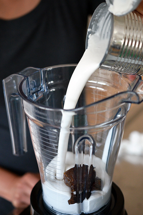 Pouring coconut milk into a blender to make dairy-free paleo vanilla ice cream