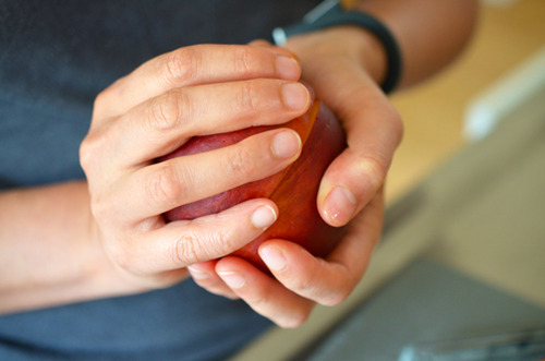 Someone using two hands to twist a cut peach open. 