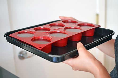Someone holding a rimmed baking sheet with a silicone ice mold filled with broth.