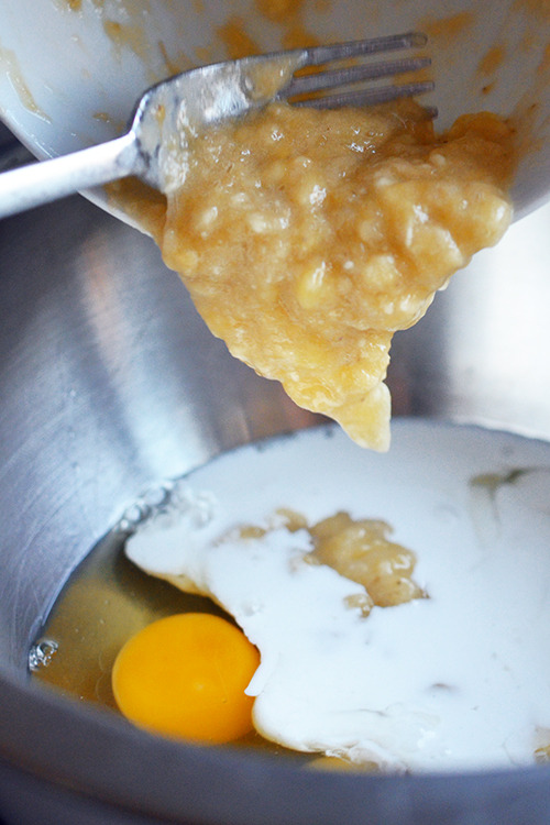 The mashed banana is added to the bowl of paleo pancake batter.